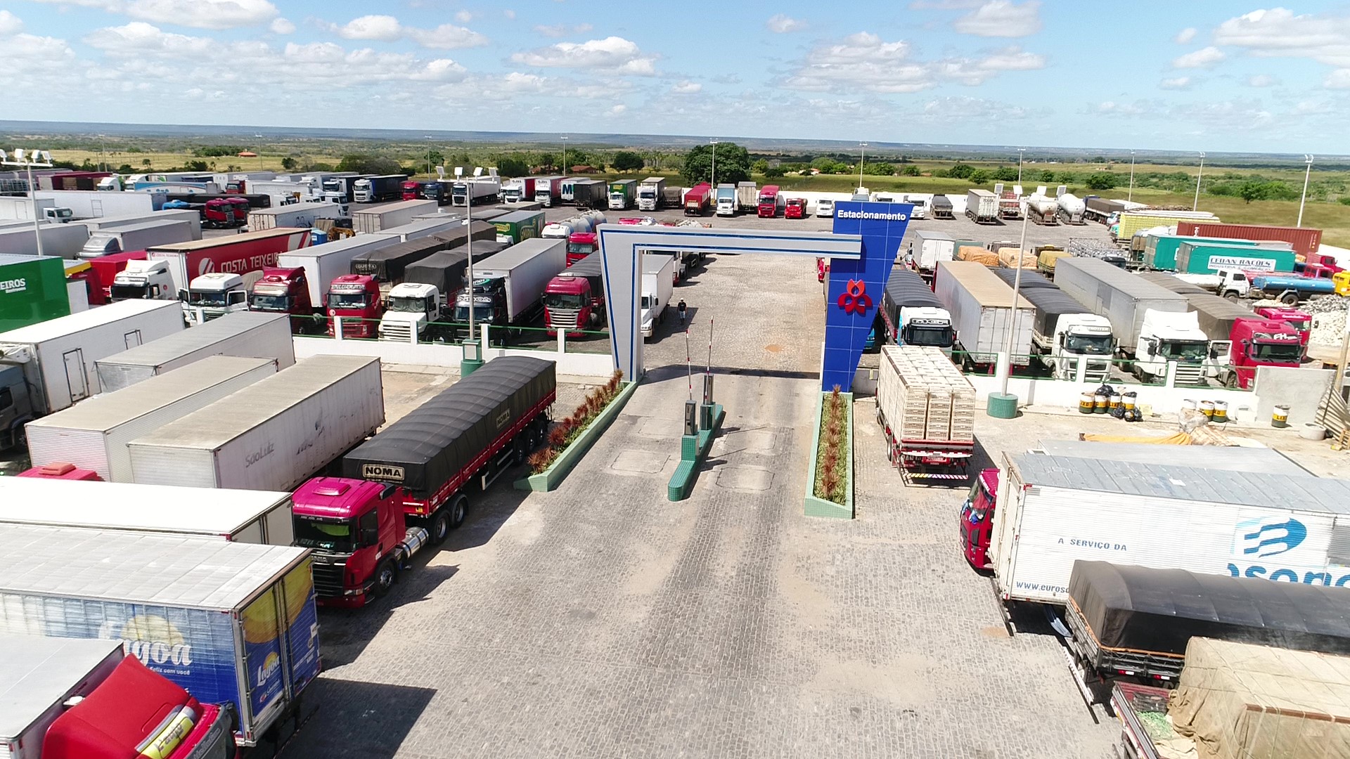 Entrada organizada e caminhões estacionados no pátio